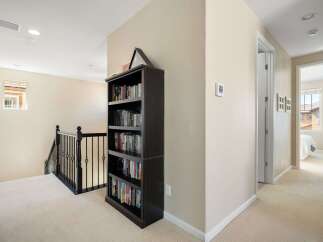 This hallway features a dark wood bookshelf filled with books, providing ample storage and a touch of classic charm.