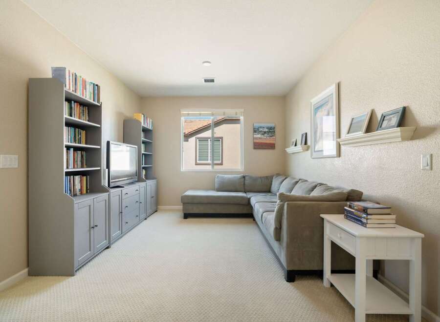 This spacious living room features a large sectional sofa perfect for family gatherings and a built-in entertainment center with ample shelving for books and media.