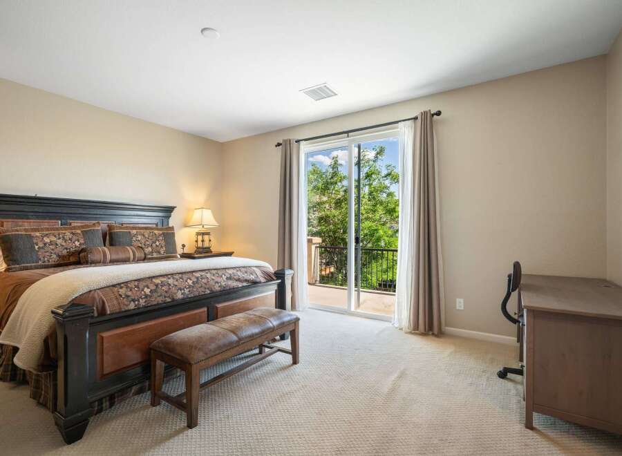 This spacious bedroom features a luxurious king-size bed with elegant bedding and a comfortable leather bench at its foot.