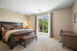 This spacious bedroom features a luxurious king-size bed with elegant bedding and a comfortable leather bench at its foot.