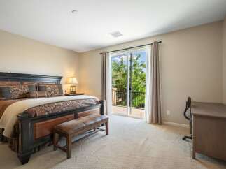 This spacious bedroom features a luxurious king-size bed with elegant bedding and a comfortable leather bench at its foot.