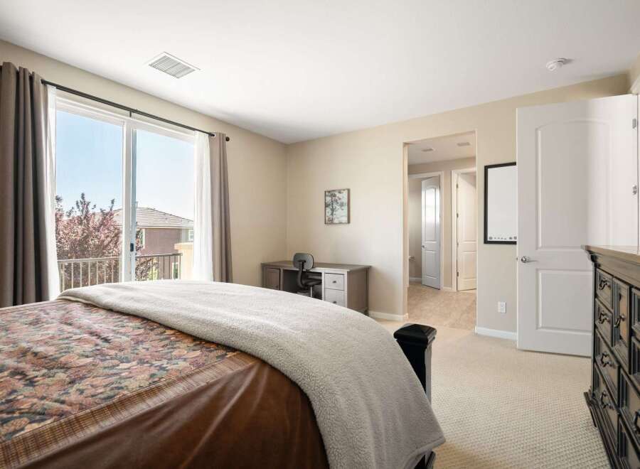 This bedroom offers a comfortable retreat with a large sliding glass door leading to a private balcony, perfect for enjoying the outdoors.
