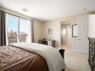 This bedroom offers a comfortable retreat with a large sliding glass door leading to a private balcony, perfect for enjoying the outdoors.