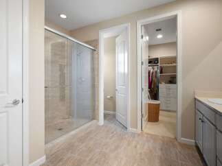 Step into this luxurious master bathroom featuring a spacious glass-enclosed shower and a walk-in closet with ample storage.