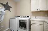 This laundry room features a stacked washer and dryer set, a utility sink, and ample cabinet storage.