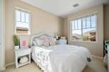 This charming bedroom features a cozy white wicker bed adorned with plush pillows and a playful rainbow accent.