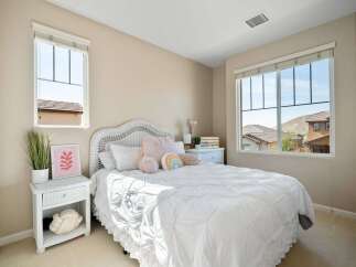 This charming bedroom features a cozy white wicker bed adorned with plush pillows and a playful rainbow accent.