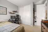 This bedroom features a comfortable bed, a dedicated gaming or study area with a computer and racing wheel, and ample storage solutions including a large closet and shelves displaying collectibles.