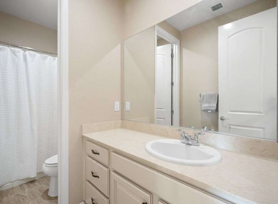 This bright and clean bathroom features a spacious vanity with ample counter space and storage, perfect for organizing your essentials.