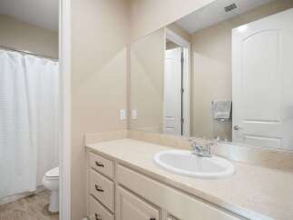 This bright and clean bathroom features a spacious vanity with ample counter space and storage, perfect for organizing your essentials.