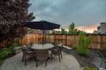 Enjoy outdoor living in this charming backyard featuring a paved patio with a dining set and umbrella, perfect for al fresco meals.