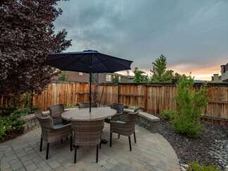 Enjoy outdoor living in this charming backyard featuring a paved patio with a dining set and umbrella, perfect for al fresco meals.