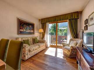 Experience comfortable living in this charming apartment, featuring a cozy living area with a floral-patterned sofa and armchair, perfect for relaxing.