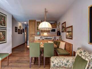 Experience cozy living in this charming dining area, featuring a built-in wooden banquette with plush green cushions, perfect for intimate meals.