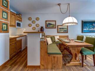 Enjoy cozy meals in this charming dining area featuring a built-in wooden banquette and a rustic wooden table.