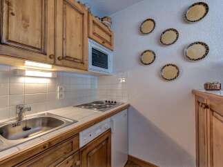 This charming kitchen features warm wooden cabinetry and a practical tiled backsplash.
