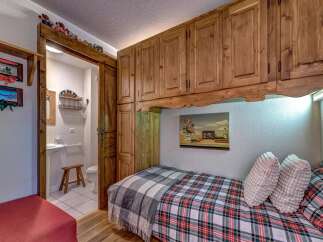 This charming bedroom features a cozy single bed adorned with a plaid comforter and throw blankets, perfect for a restful night's sleep.