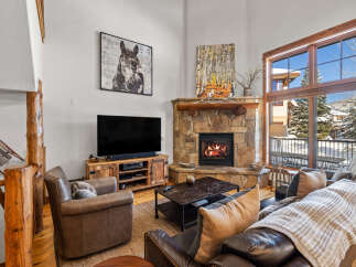 Experience rustic charm and cozy evenings in this mountain living room, featuring a grand stone fireplace and comfortable leather seating.