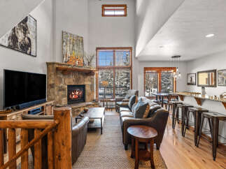 Experience rustic luxury in this stunning mountain lodge living room, featuring a grand stone fireplace and soaring vaulted ceilings.