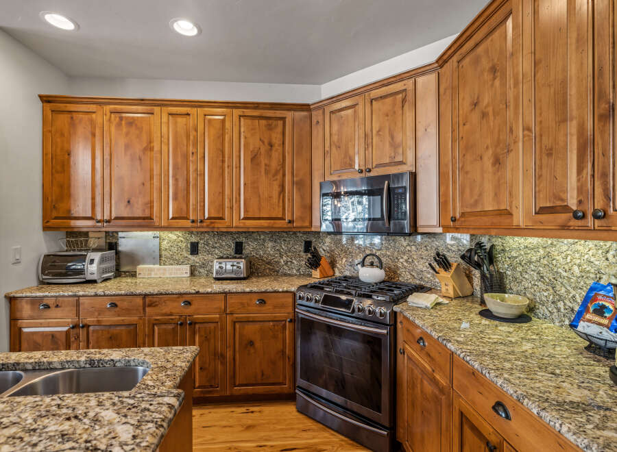 This spacious kitchen boasts beautiful natural wood cabinetry and granite countertops, offering a warm and inviting atmosphere.