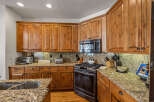 This spacious kitchen boasts beautiful natural wood cabinetry and granite countertops, offering a warm and inviting atmosphere.