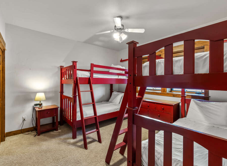 This charming bedroom features two sets of vibrant red bunk beds, perfect for accommodating multiple guests.