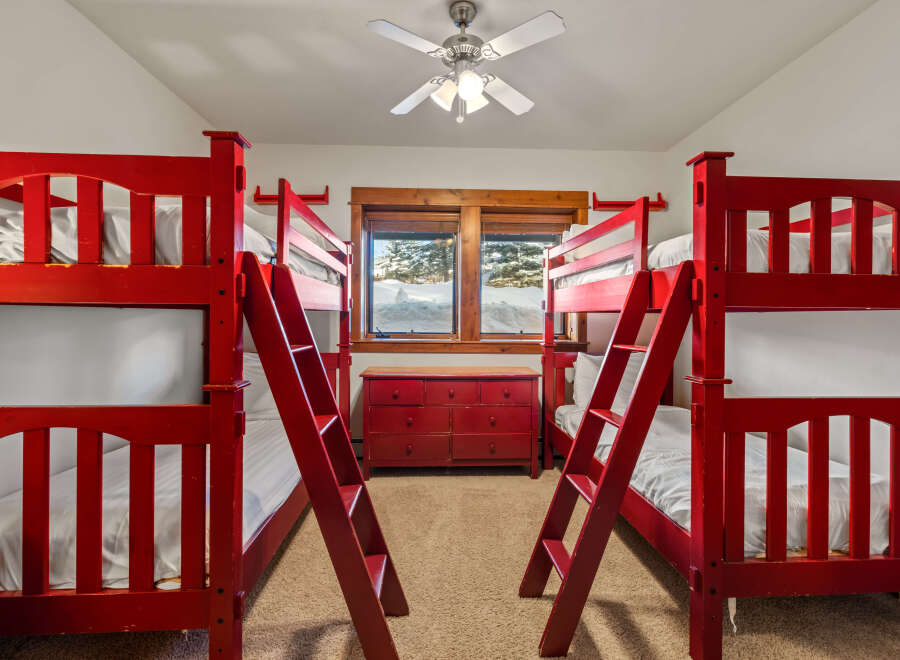 This charming bedroom features four vibrant red bunk beds, perfect for accommodating multiple guests or children.