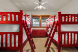 This charming bedroom features four vibrant red bunk beds, perfect for accommodating multiple guests or children.