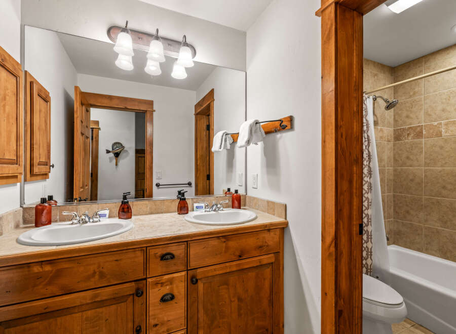 This charming bathroom features a double vanity with wooden cabinetry and granite countertops, perfect for shared living.