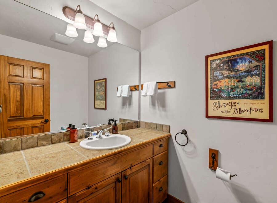 This charming bathroom features a rustic wooden vanity with a tiled countertop and a white undermount sink.