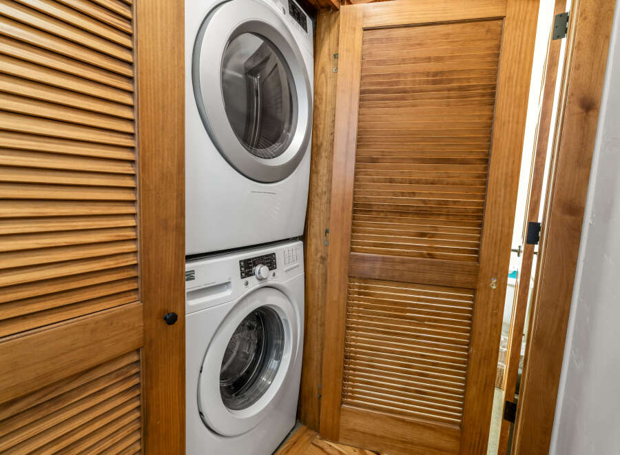 Discover the convenience of in-unit laundry with this stacked washer and dryer set, neatly tucked away behind elegant louvered wooden doors.