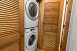 Discover the convenience of in-unit laundry with this stacked washer and dryer set, neatly tucked away behind elegant louvered wooden doors.