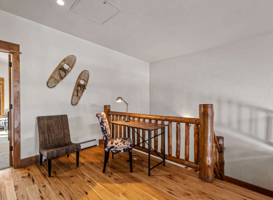 This charming loft area features a rustic wooden desk and chairs, perfect for a home office or study nook.