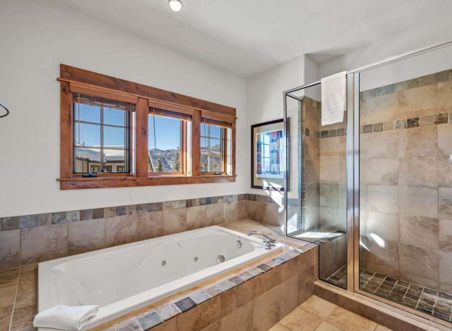 Indulge in relaxation in this luxurious bathroom featuring a spacious jetted tub and a separate glass-enclosed shower.