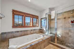 Indulge in relaxation in this luxurious bathroom featuring a spacious jetted tub and a separate glass-enclosed shower.