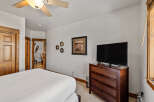 This charming bedroom features a comfortable bed, a modern flat-screen TV, and ample storage with a wooden dresser.