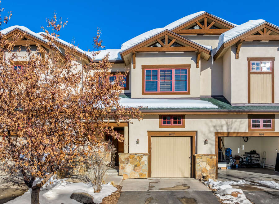 Experience mountain living in this charming townhome featuring a stucco exterior and snow-capped roofs.