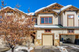 Experience mountain living in this charming townhome featuring a stucco exterior and snow-capped roofs.