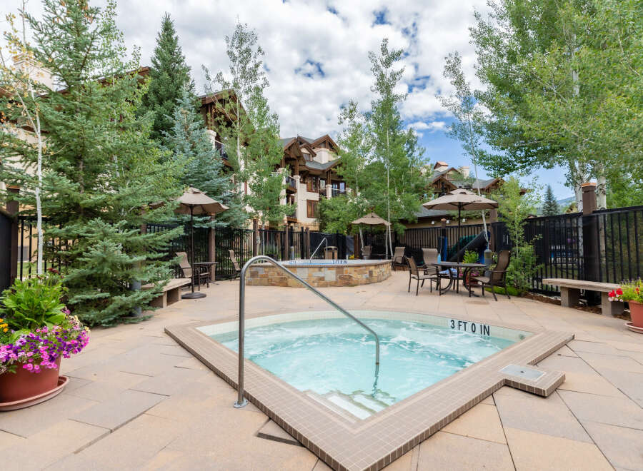 Enjoy a relaxing dip in the inviting hot tub, surrounded by lush greenery and mountain views.