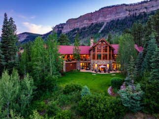 Experience luxury mountain living in this stunning lodge-style home, nestled against a majestic cliff face.