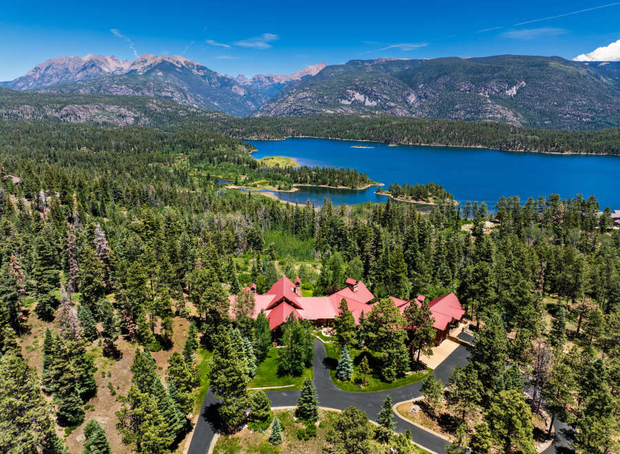 Experience luxury living in this stunning mountain estate, nestled amidst a lush pine forest with breathtaking views of a serene lake and majestic peaks.