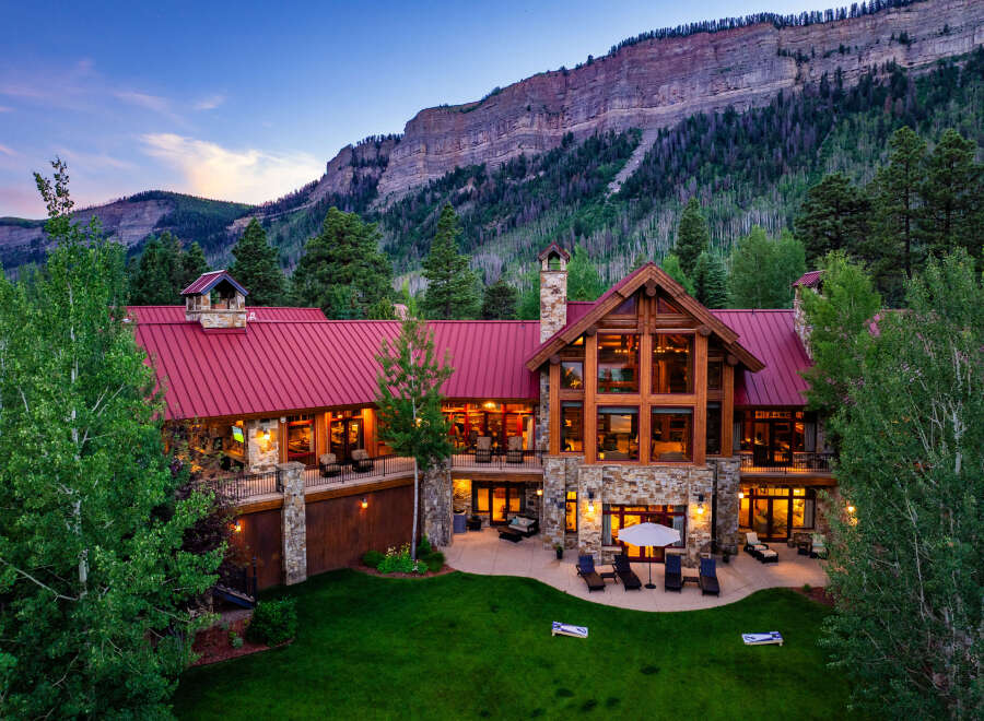 Experience luxury mountain living in this stunning lodge-style home, nestled against a majestic cliff face.