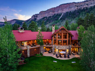 Experience luxury mountain living in this stunning lodge-style home, nestled against a majestic cliff face.