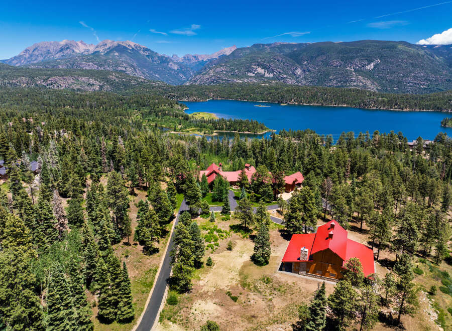 Experience luxury mountain living in this stunning estate, nestled amidst a dense pine forest with breathtaking views of a serene lake and majestic mountains.