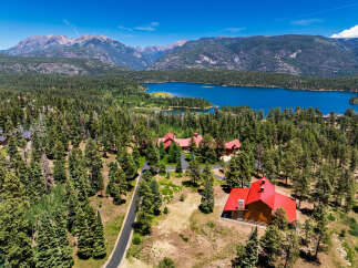 Experience luxury mountain living in this stunning estate, nestled amidst a dense pine forest with breathtaking views of a serene lake and majestic mountains.