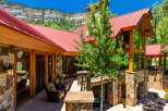 Experience luxury mountain living in this stunning stone and timber home, featuring a vibrant red metal roof and expansive windows that capture breathtaking natural views.