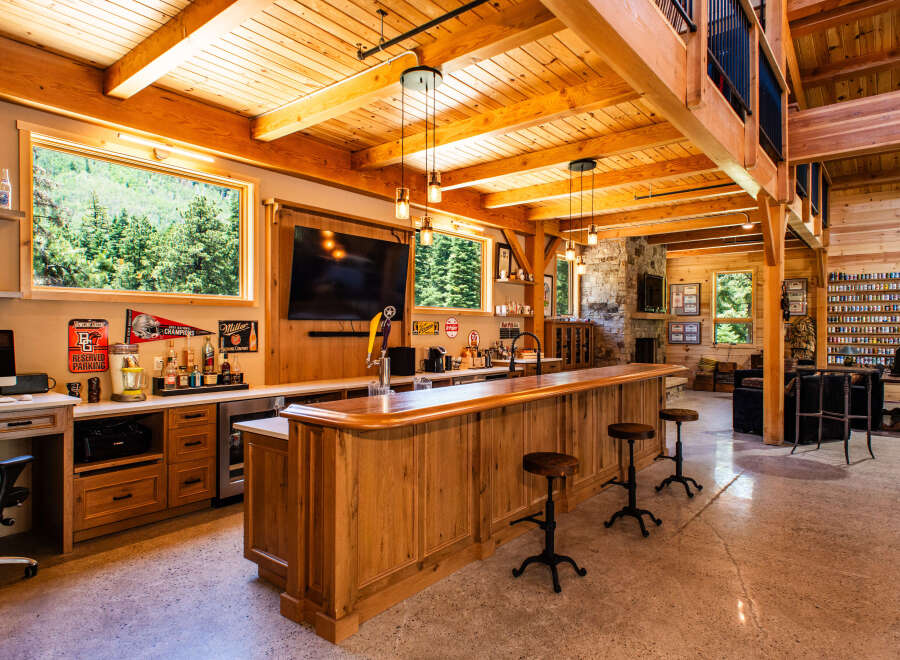 Experience ultimate entertainment in this stunning custom-built bar and lounge area, featuring a beautiful wooden bar with a built-in tap, a large television, and ample seating.