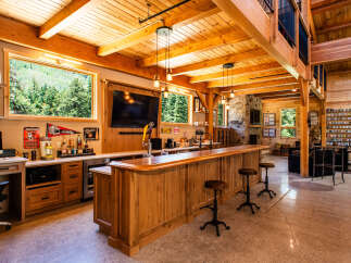 Experience ultimate entertainment in this stunning custom-built bar and lounge area, featuring a beautiful wooden bar with a built-in tap, a large television, and ample seating.