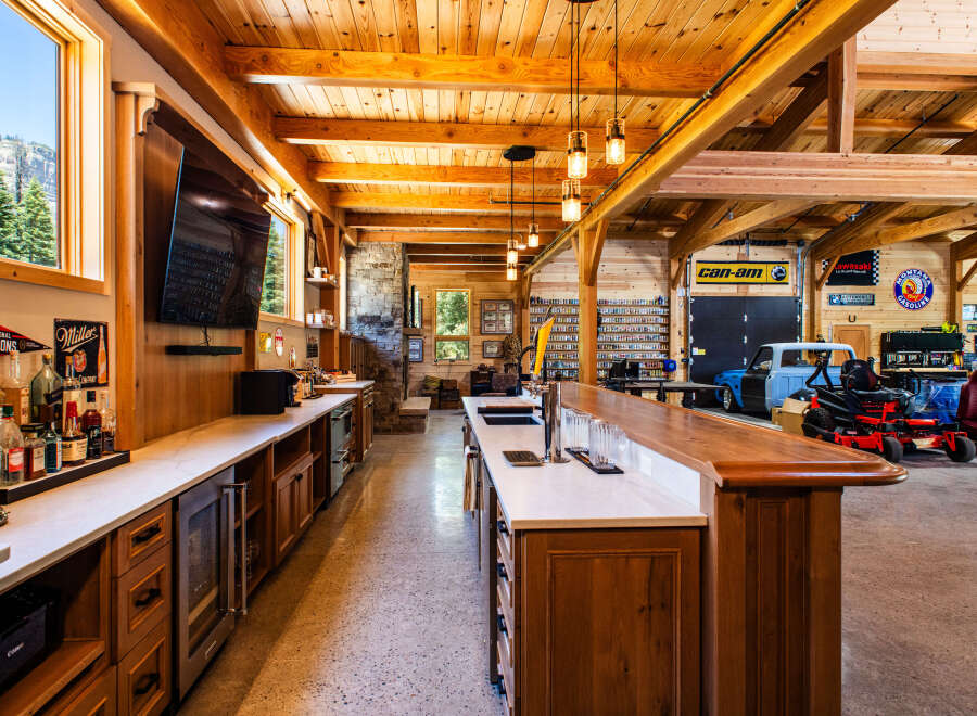 Experience the ultimate man cave with this stunning custom-built bar and entertainment area, featuring a fully stocked bar, multiple refrigerators, and a large television.