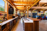 Experience the ultimate man cave with this stunning custom-built bar and entertainment area, featuring a fully stocked bar, multiple refrigerators, and a large television.